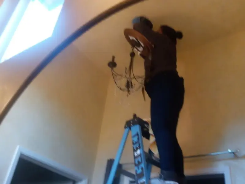 Electrician installing a chandelier in a Fortville residence